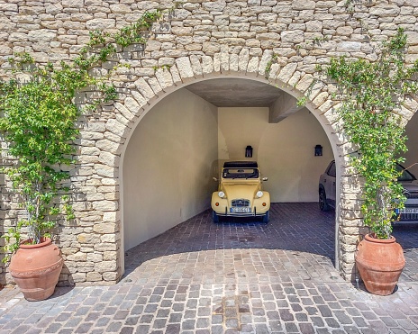 Gordes, France – August 03, 2023: A yellow Deux Chevaux parked in the garage of a stone building in Provence, France
