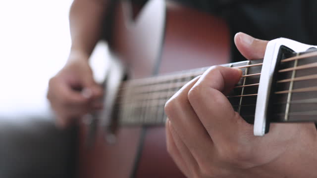 Close up a man playing guitar indoors