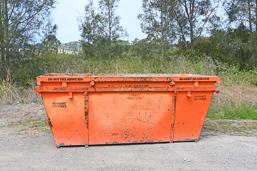 Two orange metal skip bins left on the side of a road