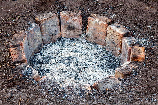 A round hearth sunken into the ground is reinforced with bricks, ash after use.