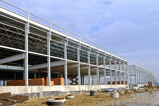 Construction of a large logistics complex made of metal structures. The frame of the building is in the process of construction.