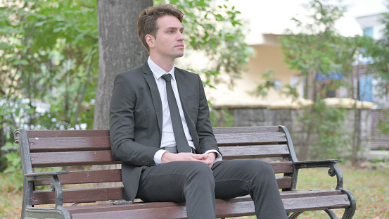Serious Young Businessman Sitting Outdoor