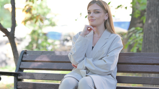 Serious Young Businesswoman Sitting on Bench