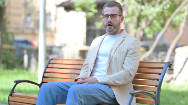 istock Shocked Middle Aged Man Looking at Camera while Sititng Outdoor 1679651212