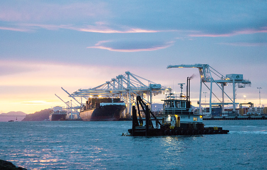 Tug boat in the Port of Oakland with an futuristic cloud formation and the setting sun.