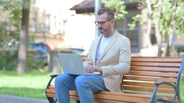 istock Middle Aged Man Working on Laptop Outdoor 1679670183