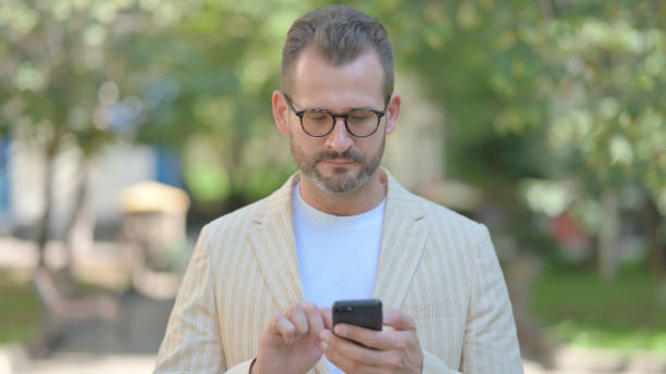 istock Middle Aged Man Browsing Internet on Smartphone Outdoor 1679671509