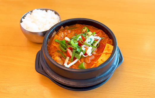 Kimchi stew with pork (kimchijjigae) soup - korean style with rice on wooden table, top view