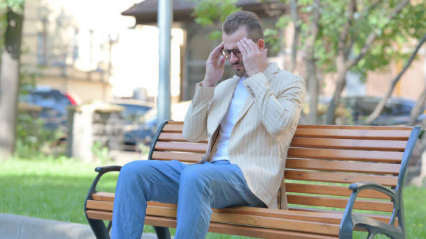 istock Tired Middle Aged Man Sitting Outdoor with Headache 1679674335
