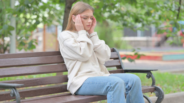 istock Young Woman Sitting Outdoor with Headache 1679683376