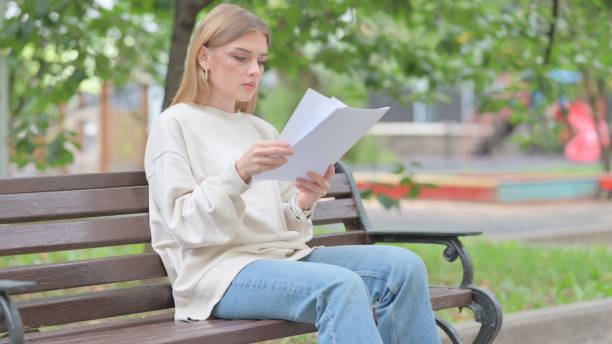istock Young Woman Reading Documents while Sitting Outdoor 1679686508