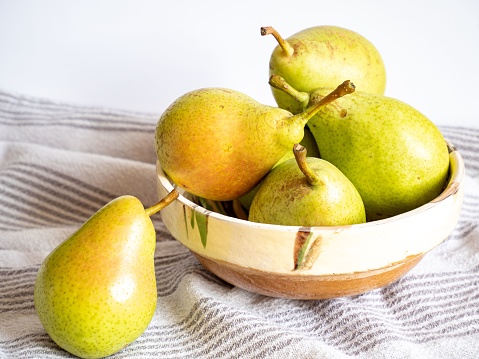 A closeup of pears in a vase on a tablecloth