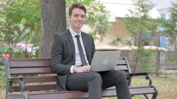 istock Young Businessman Smiling at Camera while Working on Laptop Outdoor 1679702153