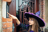 Little girl dressed up as witch ringing the doorbell on Halloween