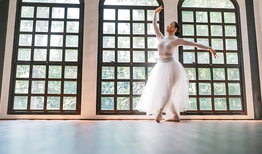 Asian girlÂ ballet dancer creative performance with white skirt demonstrating dancing skill Young gracefulÂ  ballerina training exercise body practiceÂ on studio wellness Beauty classic ballet.