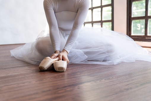Ballerina in ballet shoes. Asian girlÂ tying ribbons of toe shoes. ballet dancer preparing and wearing ballet shoes in dance studio prepares for a rehearsal