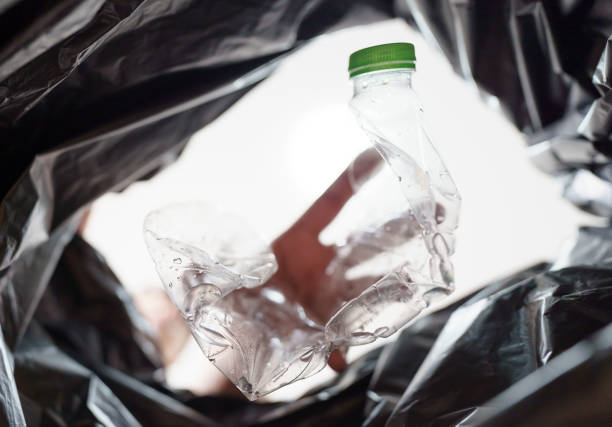 istock Image from inside yellow recycling bag of man throwing empty plastic bottle in recycling bin Home recycle eco green zero concept. 1679740105