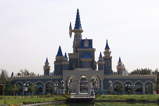 Seoul, South Korea - November 5, 2022: Amber-coloured leaves of cherry trees frame a castle at Lotte World's Magic Island in the middle of Seokchon Lake in Jamsil.