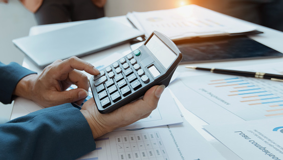 Group of  business hands working on calculator with financial market charts in office desk, Business people analysis cost graph on meeting room concept.