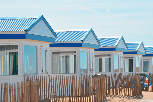 Close-up of multi colored beach huts in a row against blue sky in The Netherlands during summer. vacation travel. Outdoor relaxing at ocean with copy space - vacation and travel concept