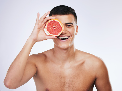 Beauty, grapefruit and skincare with portrait of man in studio for health, detox and natural cosmetics. Vitamin c, nutrition and spa with person and fruit on white background for self care and glow
