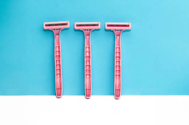 Photo of Pink lady shavers, razors on white, blue background