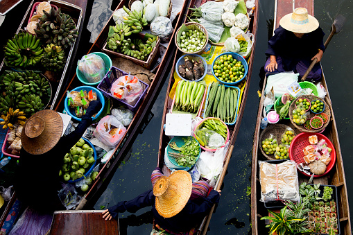 29th January, 2016 - Bangkok, Thailand: Bustling with activity, the floating market in Bangkok is a vibrant mosaic of colors and sounds. Market traders skillfully navigate their boats, laden with a variety of local produce and goods, while boat excursion operators guide tourists and local buyers through the waterways. The scene is a lively showcase of traditional Thai commerce and culture, with visitors engaging in the unique experience of shopping on water.