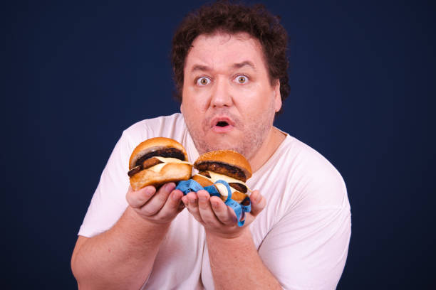 istock Funny hungry fat man eating burger. 1679838539