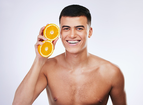 Adult man squeezing orange fruit directly in his mouth