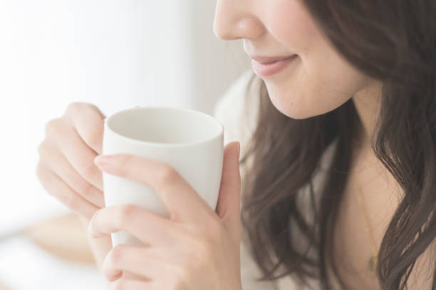 女性が飲み物を飲んでいます。 - 温かい飲み物 ストックフォトと画像