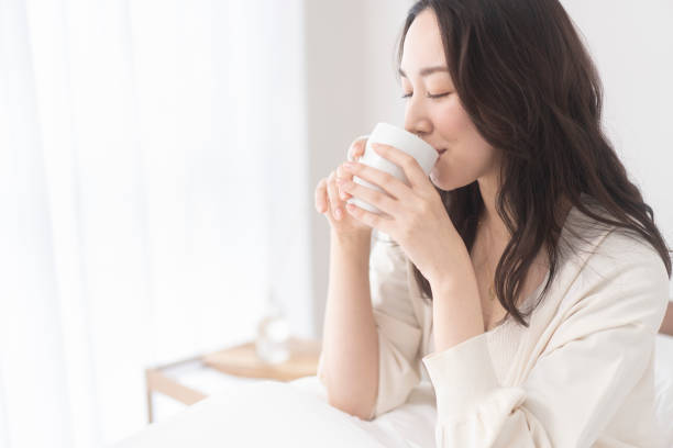 A woman is drinking a drink. A young Japanese woman is holding a white cup and drinking a drink. only japanese stock pictures, royalty-free photos & images