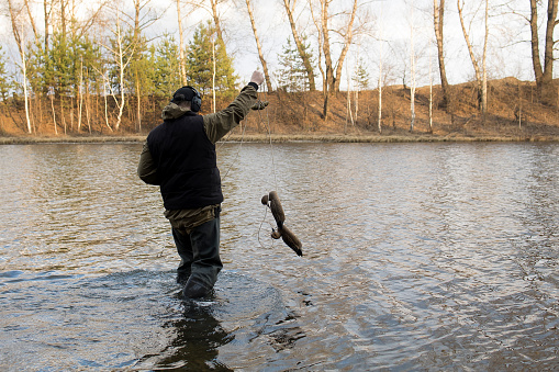 Hunter man hunts with a gun for ducks on the river bank