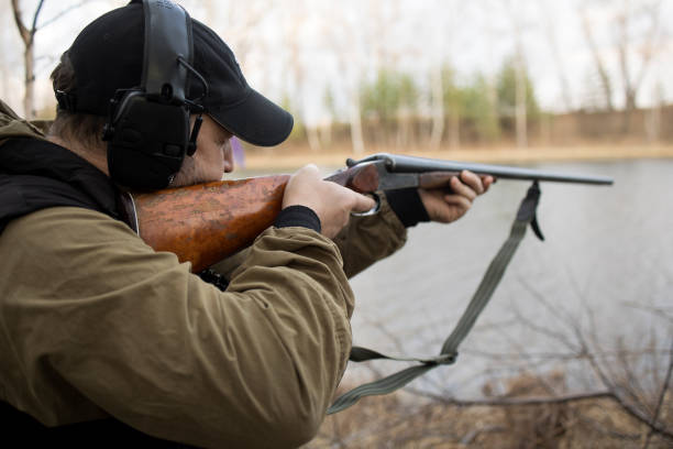 istock Hunter man hunts with a gun for ducks on the river bank 1679859470