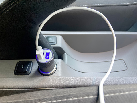 Close-up charging smart phone cable connected to USB port in car. Car USB and aux port