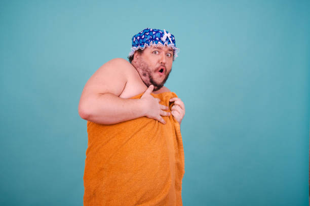 istock Funny fat man is washing himself in the shower. 1679867558