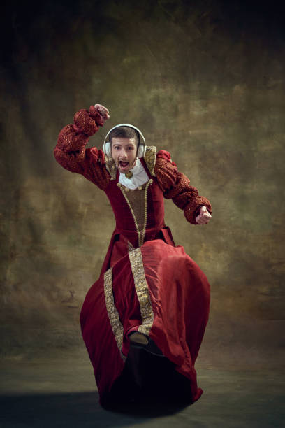 młody mężczyzna, średniowieczny książę, monarchini w kobiecym stroju słuchający muzyki w słuchawkach i tańczący na tle vintage - haute couture audio zdjęcia i obrazy z banku zdjęć