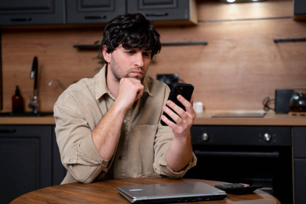 istock A young businessman sends messages on a smartphone while sitting at a table in the kitchen 1679875197