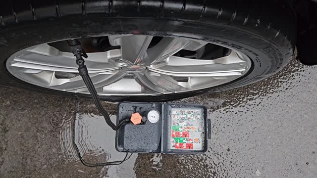 On a wet asphalt road, one of the tires is completely flat and pump