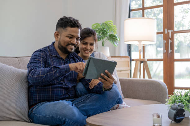 istock Happy Young couple using a digital tablet together while relaxing on couch sofa at home 1679894526