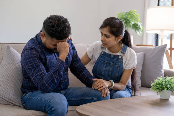 Indian young cuople stress relief trust talk share disappointment suffer serius pain sick sorrow cry man and wife encourage him at sofa