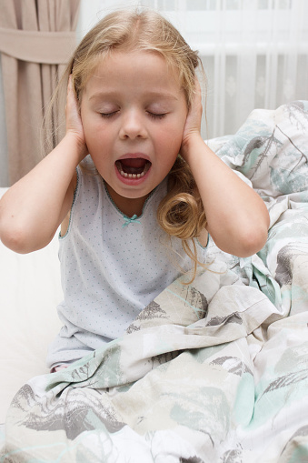 Little child closing ears with hands. The fear of loud sounds, ache or noise