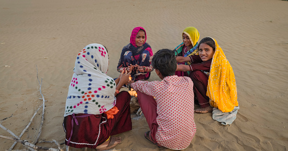 Indian kids resting on sand dune, next to a bonfire, Thar Desert, Rajasthan, India