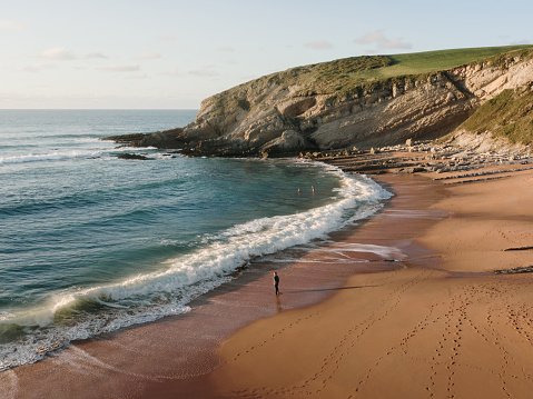 A man on a beach at sunset as seen from above