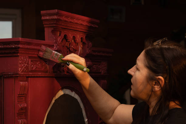 fêmea com pincel na mão e pintura ornamentos esculpidos de armário antigo maciço feito de madeira. dar vida nova a coisas antigas. restauração manual de móveis antigos - patination - fotografias e filmes do acervo