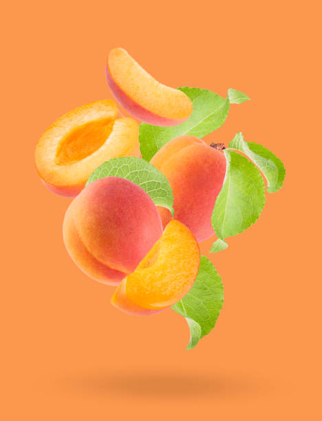 сочный оранжевый абрикос с розовой стороной, зеленые листья крупным планом летят потоком, художественная композиция. целые, половинчатые, � - georgia peach стоковые фото и изображения