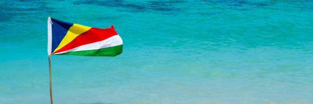 istock Seychelles flag on a beach, turquoise water panoramic background with copy space, Seychelles travel web banner 1679998176