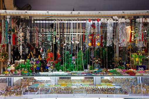 Local jewelry store shop for sale handicraft decorations and handmade bracelet stone bead accessories and ornament jade to thai people foreign travelers visit at craft market in Kanchanaburi, Thailand