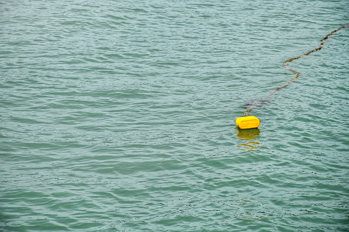 Yellow buoy on the water that is broken indicates the danger zone of the sea,On the background of the sea and waves, swim safely,Ship passenger area.