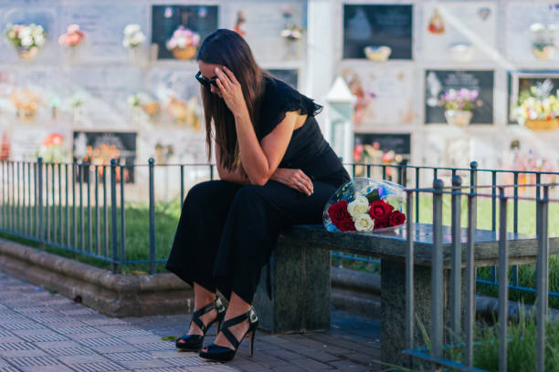 femme en pleurs assise sur un banc dans un cimetière - dead body photos et images de collection