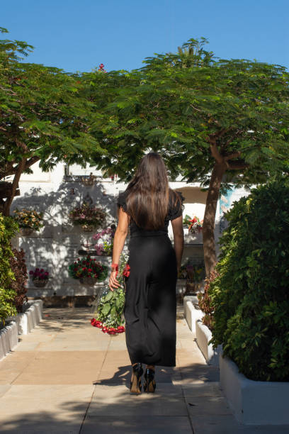 femme avec bouquet de fleurs vêtue de noir dans un cimetière - dead body photos et images de collection